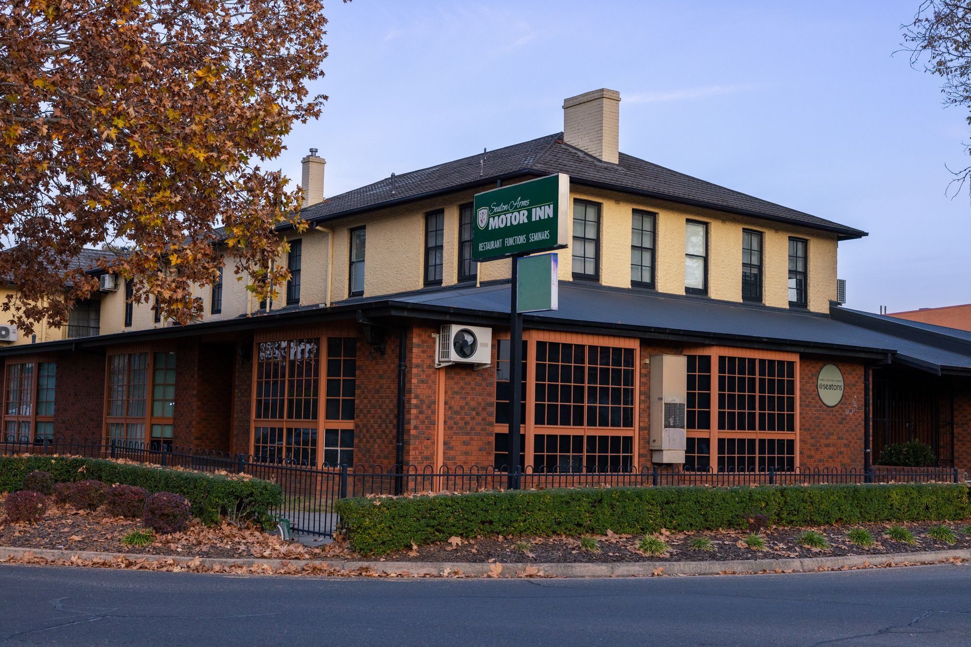 Street-facing view of Seaton Arms Motor Inn with autumn trees and heritage-style architecture.